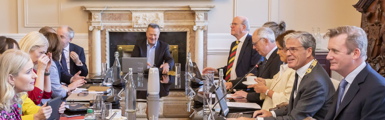 Legal professionals and members of the Law Soicety Council sit around a long table with laptops and water bottles